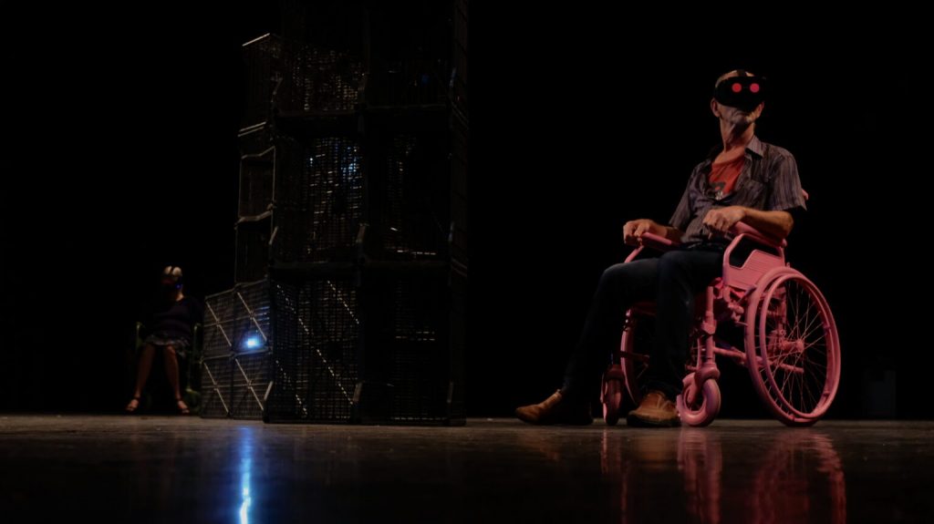 Een danser zit met een VR bril in een rolstoel voor de voorstelling Wheels 360